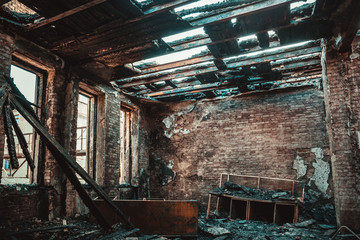 Burned brick house interior with burnt furniture, ruined building room after fire inside