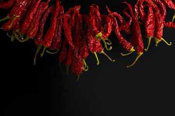 Wreath of dried chili pepper on a black background. Place for text. Wrinkled texture after drying red chili pepper
