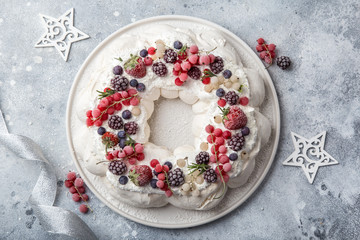 Obraz na płótnie Canvas Meringue pavlova wreath cakes with whipped cream and frozen berries