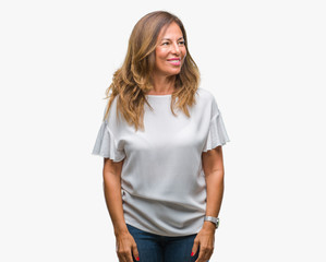 Middle age senior hispanic woman over isolated background looking away to side with smile on face, natural expression. Laughing confident.