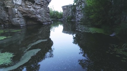 Mountain pond at ancient split rocks with marsh in the Carpathians in summer