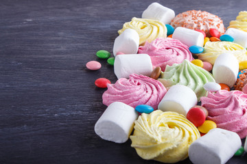 mixed multicolored candies on black wooden background.