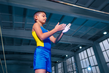 The little boy before sports gymnastics on a parallel bars at gym. The performance, sport, acrobat, acrobatic, exercise, training concept