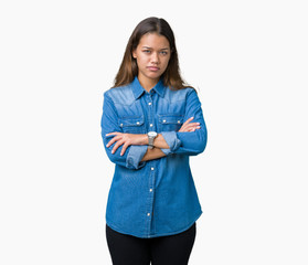 Young beautiful brunette woman wearing blue denim shirt over isolated background skeptic and...