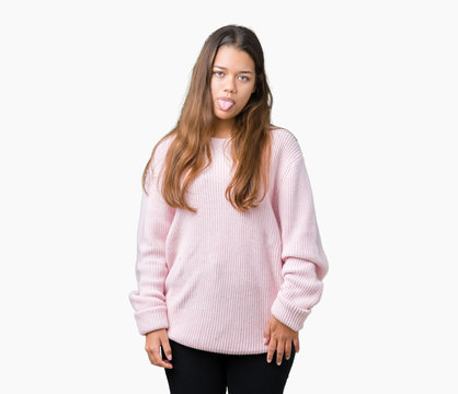 Young beautiful brunette woman wearing pink winter sweater over isolated background sticking tongue out happy with funny expression. Emotion concept.