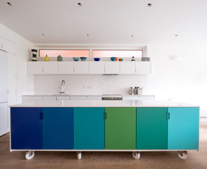 Custom designed kitchen island in open plan kitchen on industrial castor wheels, retro design painted in blue and green ombre colours.