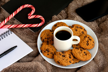 Cozy winter composition with homemade chocolate cookies, book, notebook on soft blanket. Holiday relaxation.