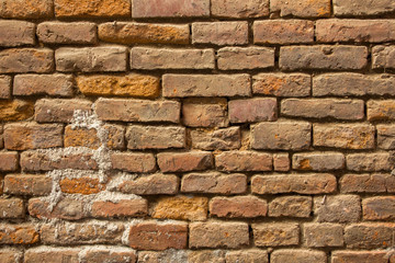 old not neat red brick wall. rough surface texture. heavily damaged brickwork