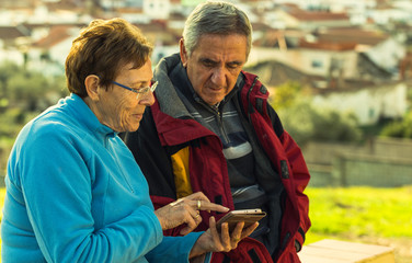 Mature woman with glasses shows something on her smartphone to her husband