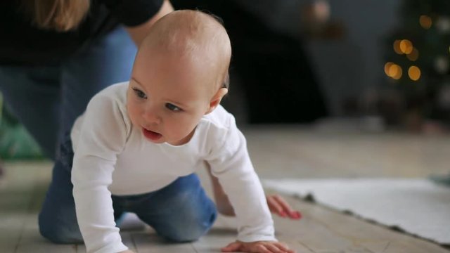 Little kid with toy in mouth crawling on sofa. Close up of naked baby in diapers walking on bed with toy. Funny child learning walk. Cute baby crawl at home. Sweet child play