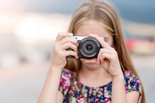 Beautiful little girl with camera takes a picture, summer outdoor