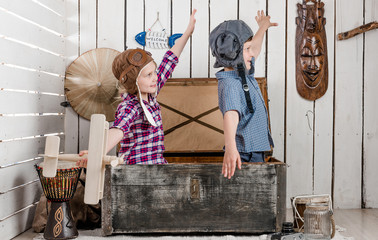 two little children-pilots fly with hands sitting in big old chest