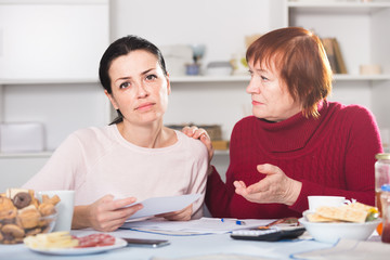 Sad young female and mother with financial documents