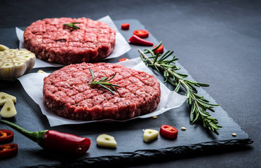 Raw cutlet of minced meat with ingredients on a dark cooking background