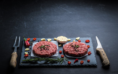 Raw cutlet of minced meat with ingredients on a dark cooking background
