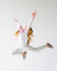 Beautiful gymnast girl in grey sportswear, performing art gymnastics element, jumping, doing split leap in the air