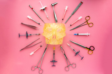Flat lay of medical instruments with human skull on rose background. Mock up health care medical background.