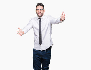 Young handsome business man wearing glasses over isolated background looking at the camera smiling with open arms for hug. Cheerful expression embracing happiness.