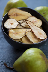 Bowl of crispy fruit chips made of pear and ripe pears, vertical shot
