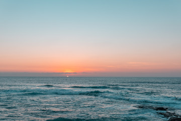 Sunset above sea or ocean. Wavy surface of water. Horizon line. Teal and orange colors concept