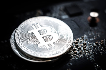 Shiny silver bitcoin on the top of a stack from bronze and silver bitcoin on computer board