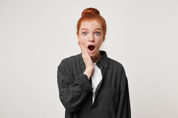 Red-haired girl stands in a daze, shocked by what she saw, with wide eyes looking at the camera,...