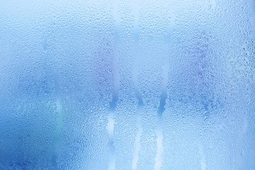 Misted glass background. Strong humidity in wintertime. Water drops from home condensation on a window