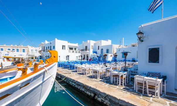 Colored tables and chairs outdoors in traditional Greek cafe. Typical Greek taverna in Naoussa port, Paros island, Greece