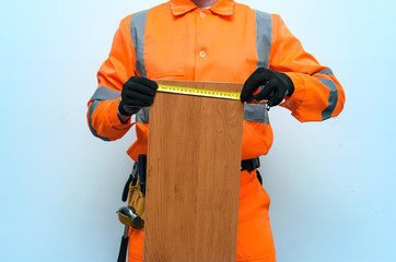Carpenter makes a measurement of a furniture board by a construction meter isolated on blue...
