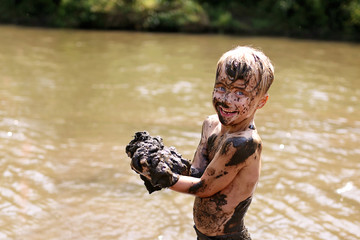 Muddy Little Boy Child Laughing as He Swims and Plays Outside in River