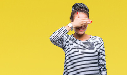 Young braided hair african american girl wearing sweater over isolated background smiling and laughing with hand on face covering eyes for surprise. Blind concept.