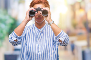 Senior caucasian woman looking through binoculars over isolated background with a confident...