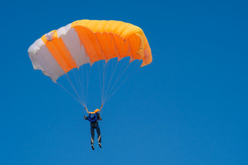Skydiver is flying with parachute in blue sky