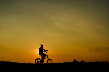 Fototapeta na wymiar silhouette of cyclist riding a bike on sunset