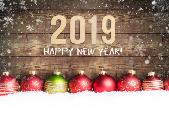 Holzwand mit Aufschrift "2019 - Happy new year!" und Weihnachtsdekoration im Schnee