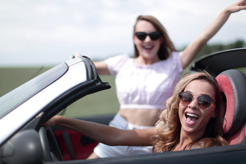 close up.two happy young women in a convertible car