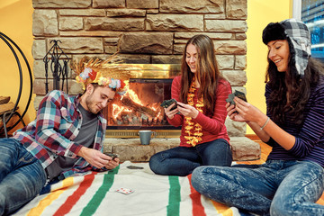 Young people playing cards by a fireplace