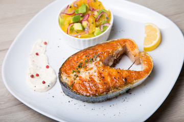 Grilled salmon, salad with oranges and avocado. Close-up, selective focus.