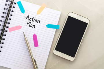 Action plan text on note pad with smart phone and pen.