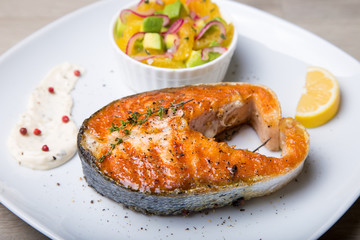 Grilled salmon, salad with oranges and avocado. Close-up, selective focus.