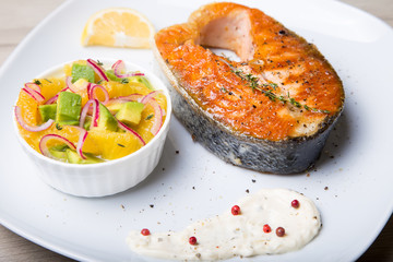 Grilled salmon, salad with oranges and avocado. Close-up, selective focus.