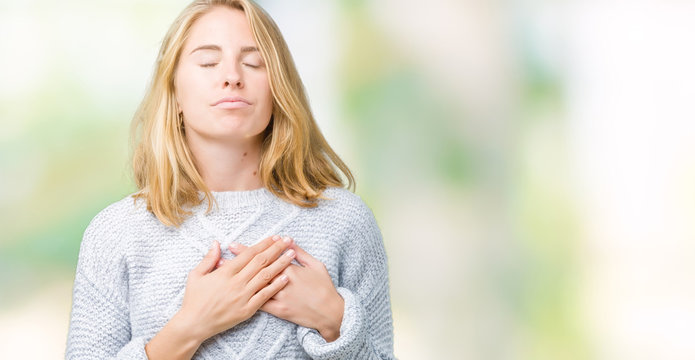 Beautiful young woman wearing winter sweater over isolated background smiling with hands on chest with closed eyes and grateful gesture on face. Health concept.