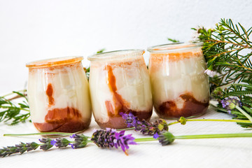 three white natural yogurts with marmalade on the bottom of the glass vase 