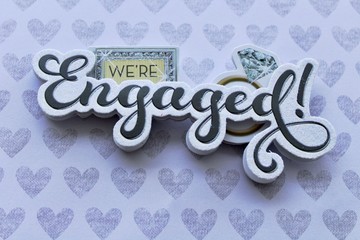 we're engaged written in 3d on a background with silver hearts close up