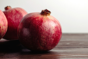 Group of pomegranate fruits on the dark wooden planks and white background