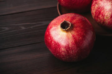 Group of pomegranate red fruits on the dark wooden background