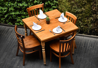 A wooden restaurant table with four wooden chairs seen from above.
