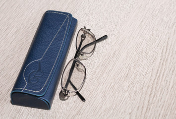 Tinted glasses and eyeglass case on grey wooden table. Background.