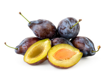 Heap of ripe plums and two halves close-up on a white background.