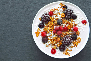 Colorful healthy breakfast bowl with berries, yogurt and granola. Top view.